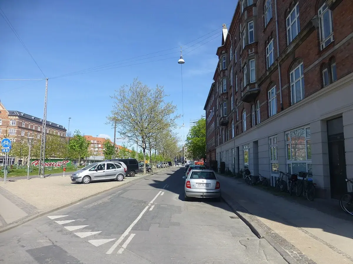 Sunny street in Nørrebro, Copenhagen with parked cars and apartment buildings.
