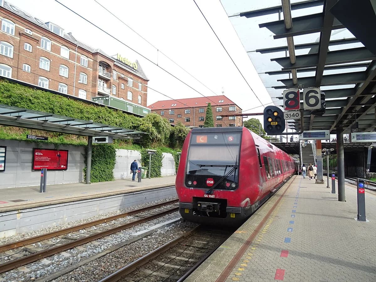 A red S-train at Valby Station beside platform signals.