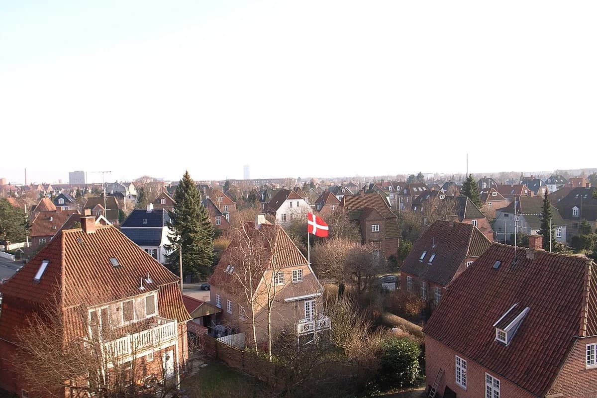 Panoramic view of rooftops in Valby, Copenhagen, with a Danish flag.