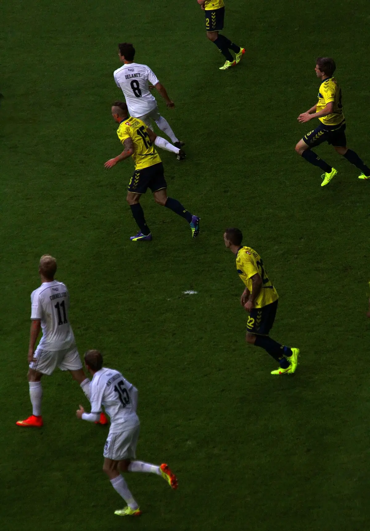 Soccer players from FCK and Brøndby competing on a stadium pitch.