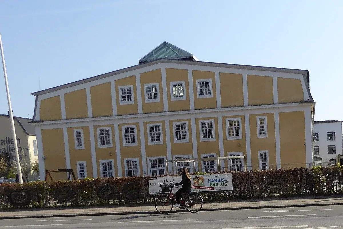 A yellow school building on a street with a cyclist passing by.