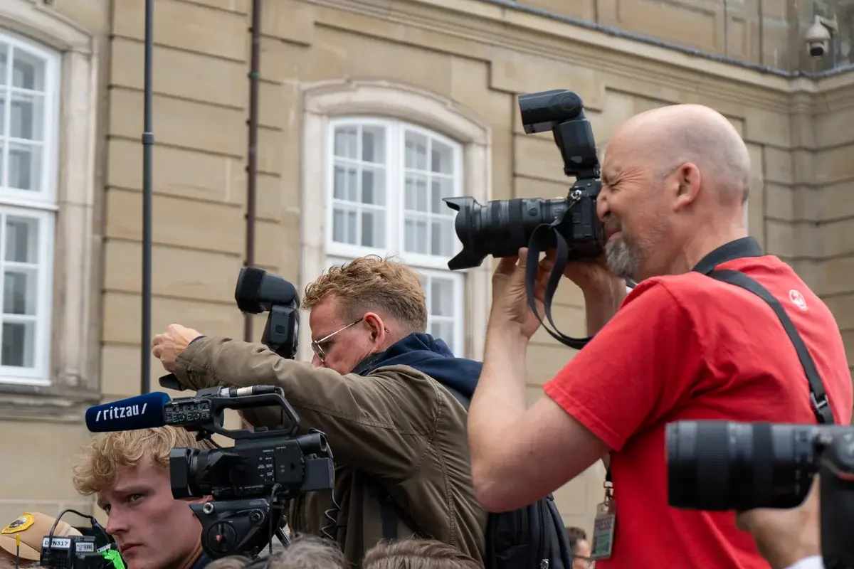 Press photographers with cameras outside Amalienborg in Copenhagen.