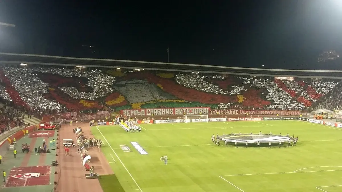 Nighttime football stadium with a large crowd display before a UEFA match.