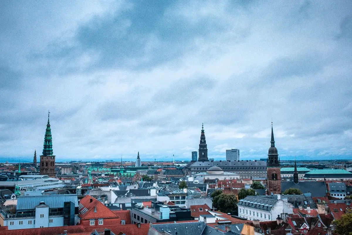 Wide panoramic view of Copenhagen's historic skyline under cloudy skies.