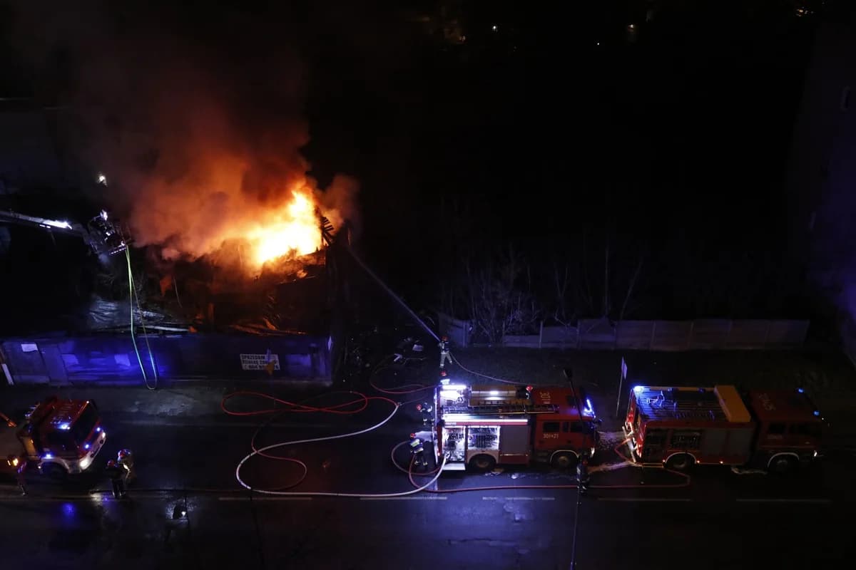 Firefighters fight a building fire at night.