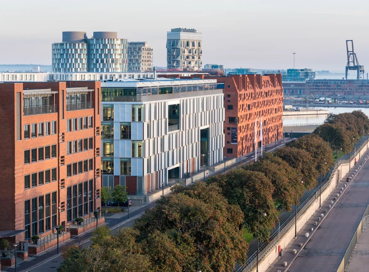 Modern office and apartment buildings along a waterfront street in Copenhagen.