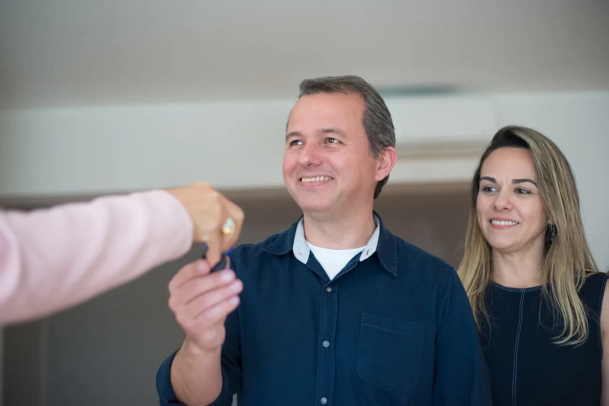 Smiling couple receiving keys indoors