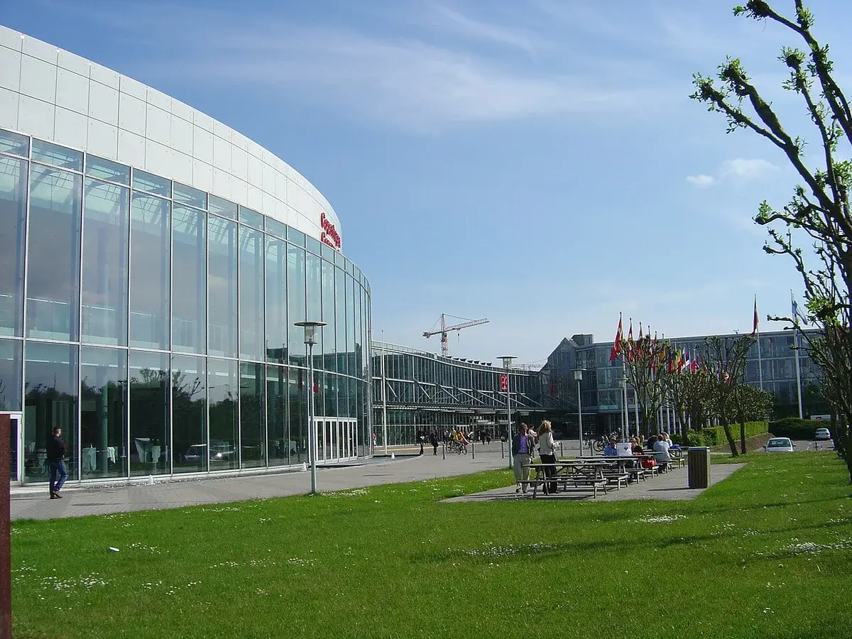 Exterior view of the Bella Center conference complex in Copenhagen with glass buildings and flags.
