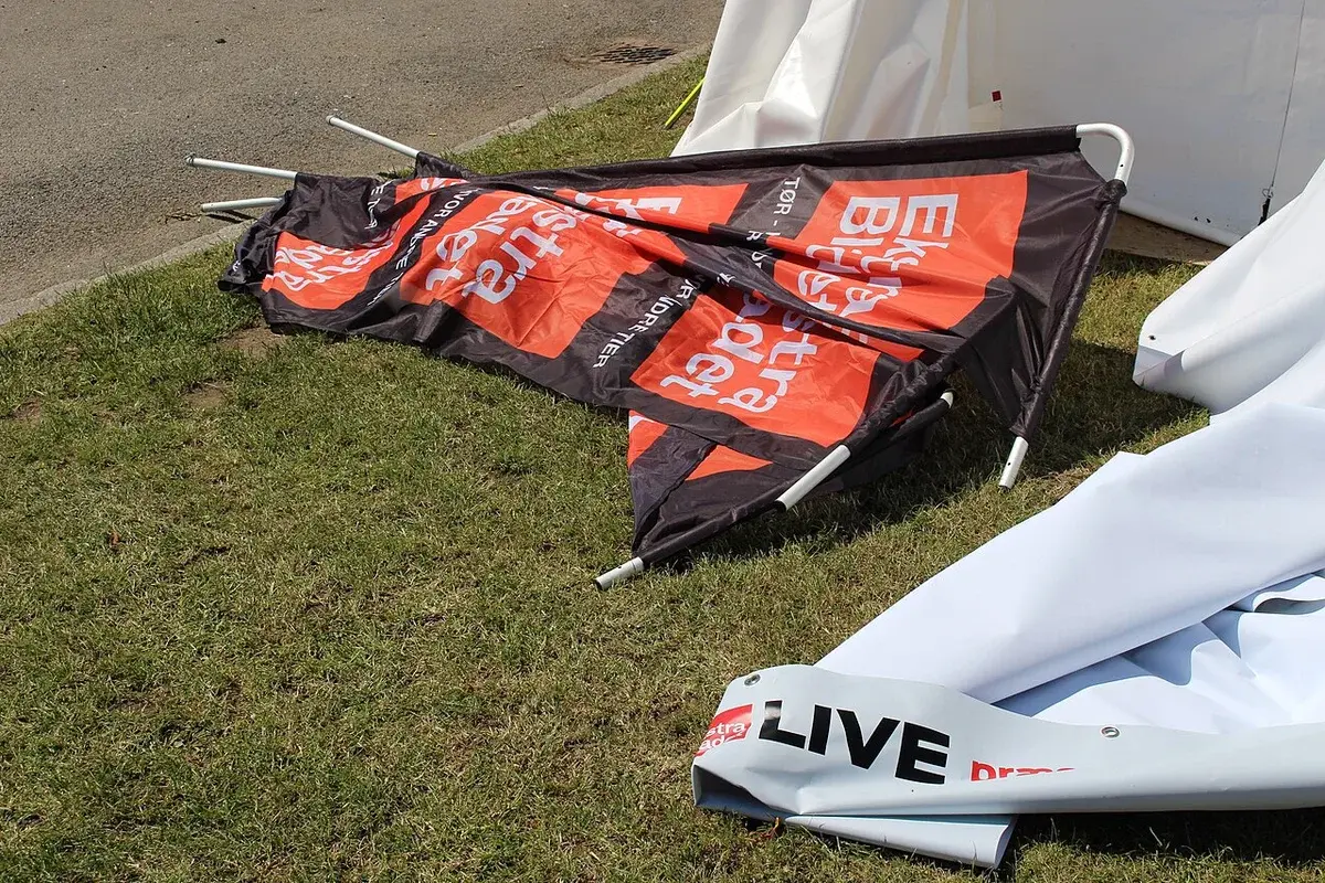 Folded Ekstra Bladet banner and tent material on grass beside a tent.