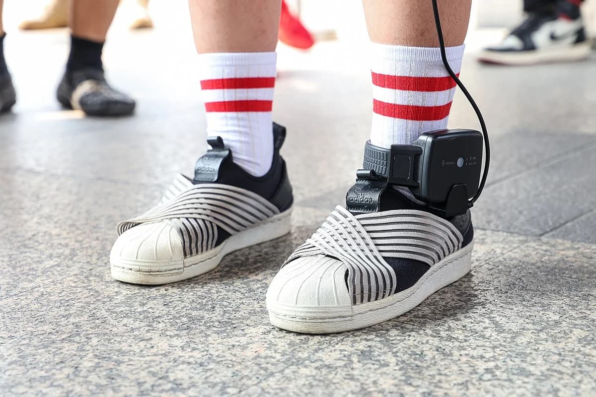 Close-up of electronic ankle monitor strapped to shoe and ankle