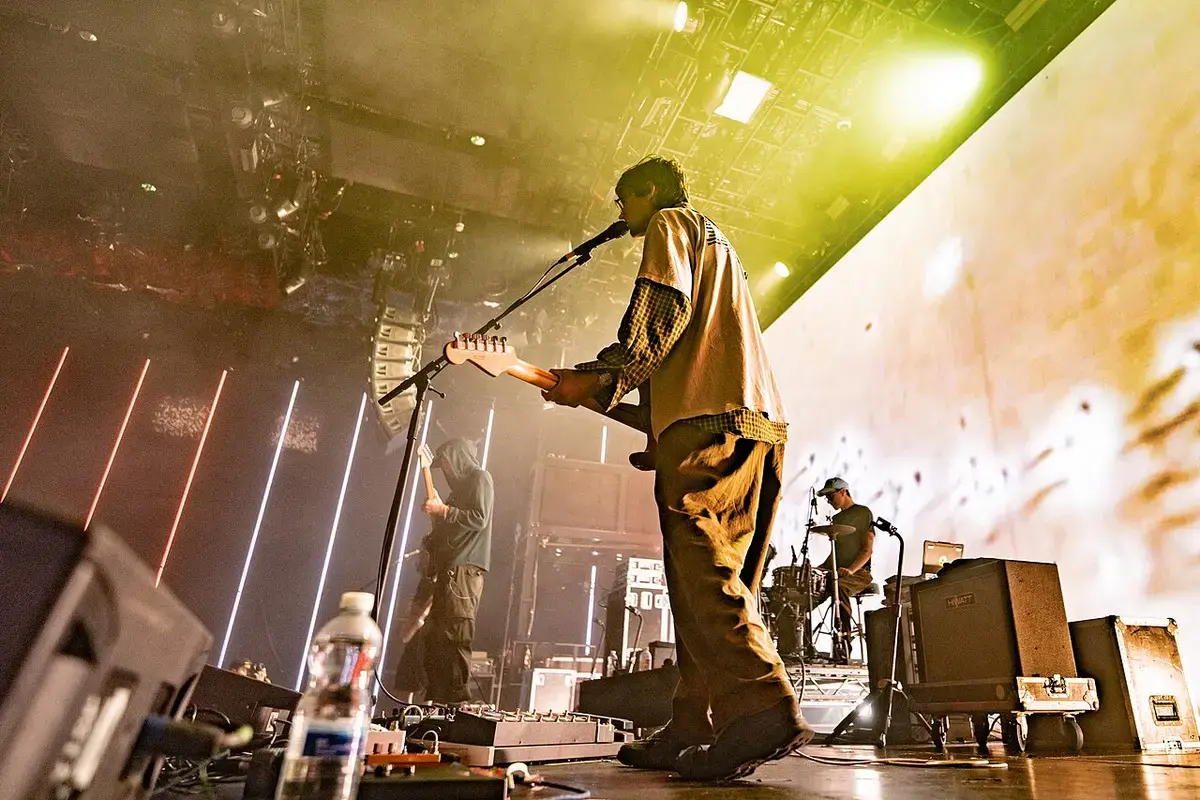 DIIV performing on stage under yellow lights at Here at Outernet in London.