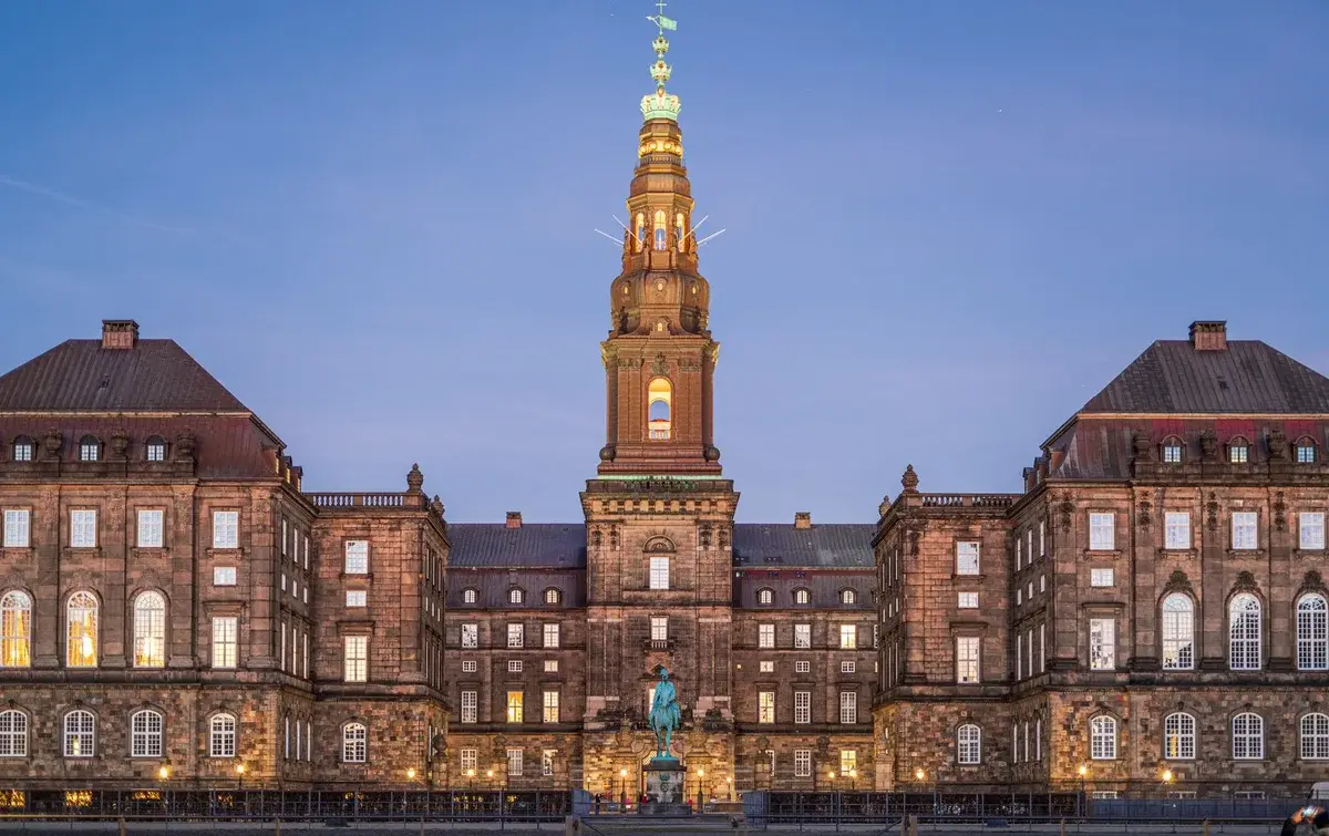 Christiansborg Palace in Copenhagen lit up at dusk with its central tower.