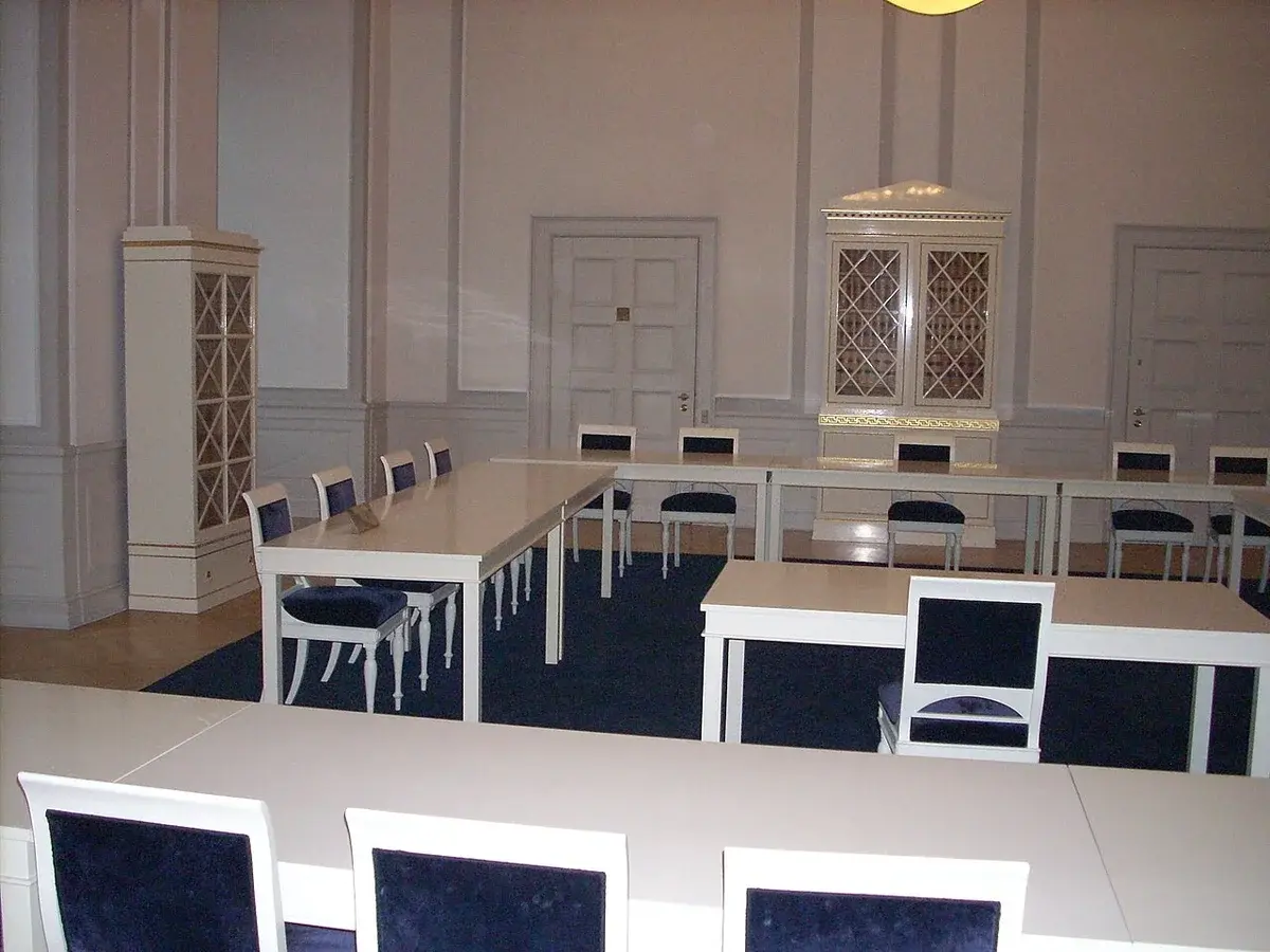 A formal courtroom with white tables and dark chairs in the Supreme Court of Denmark.