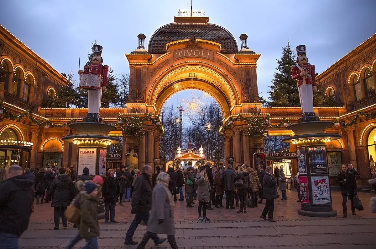 Illuminated Christmas entrance to Tivoli Gardens in Copenhagen with crowds of visitors.