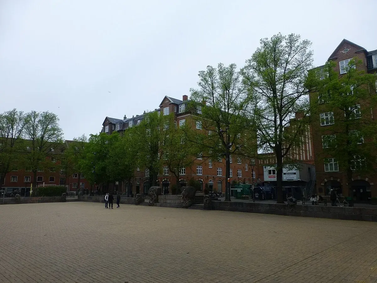Open square surrounded by brick buildings and trees in Copenhagen.