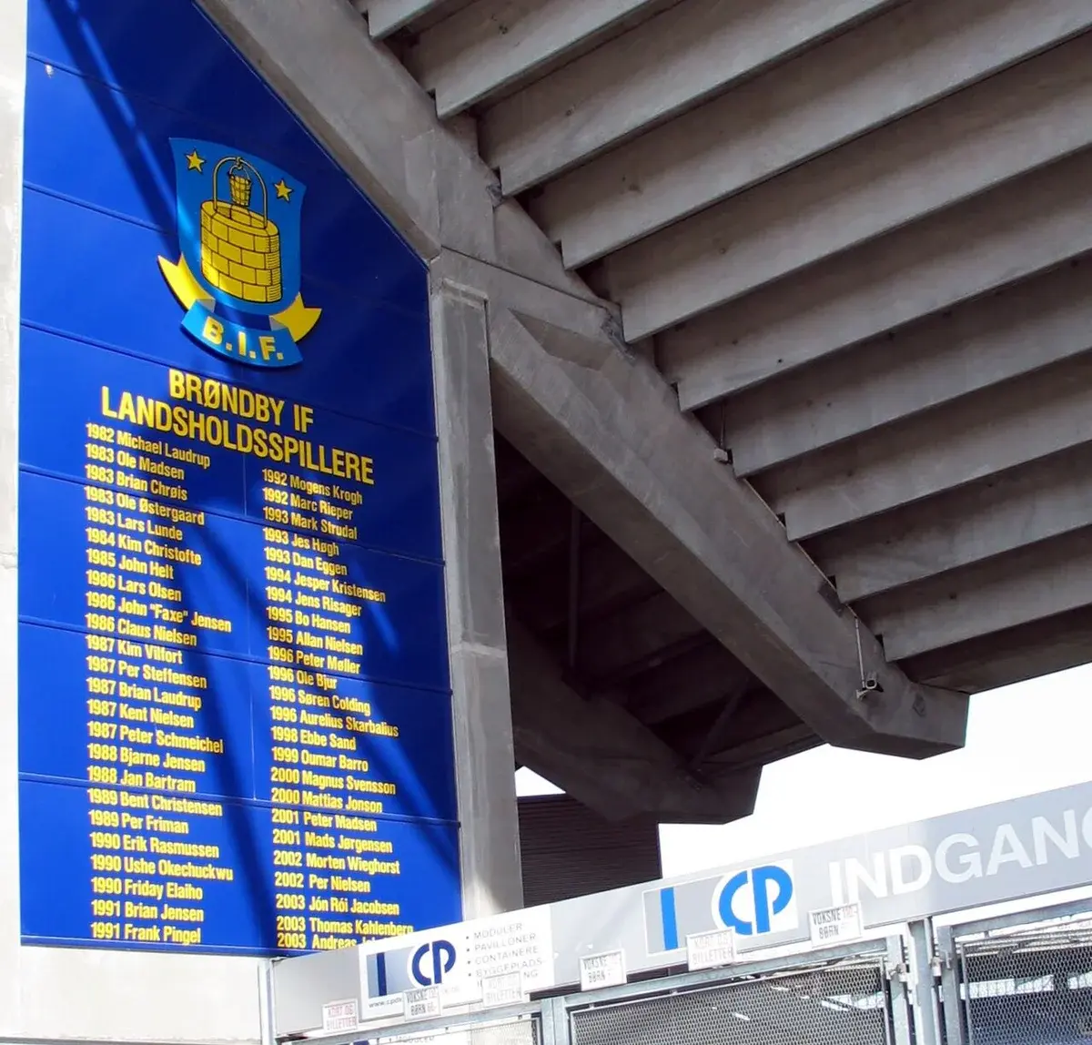 Blue Brøndby IF plaque listing players under the concrete stands at a Danish stadium entrance.
