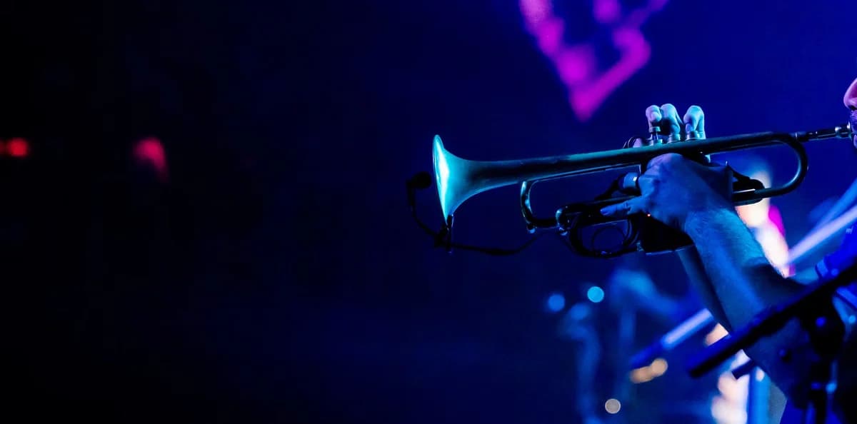 Close-up of a trumpeter playing on stage in blue concert lighting.