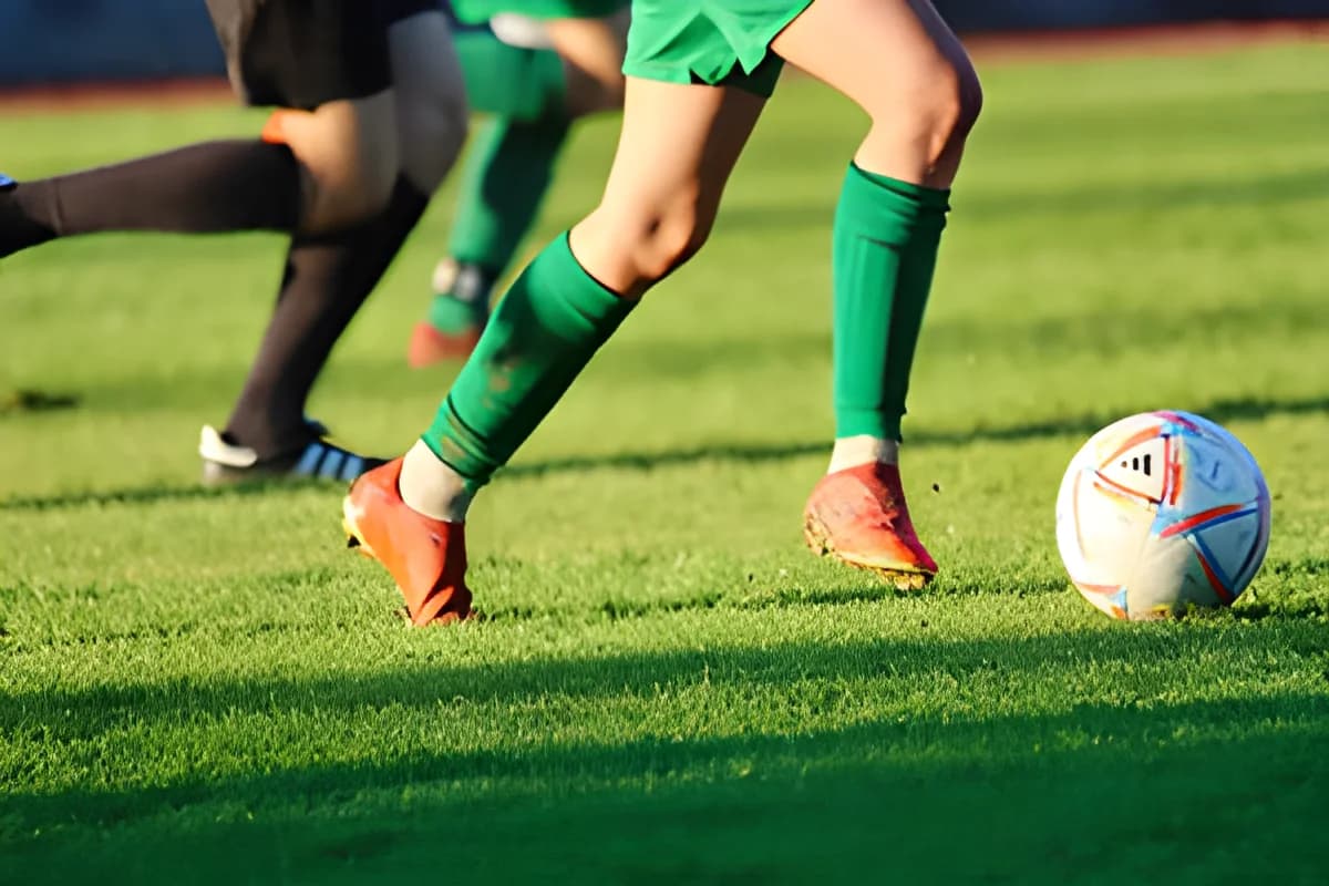 Players' legs chasing a soccer ball on the field