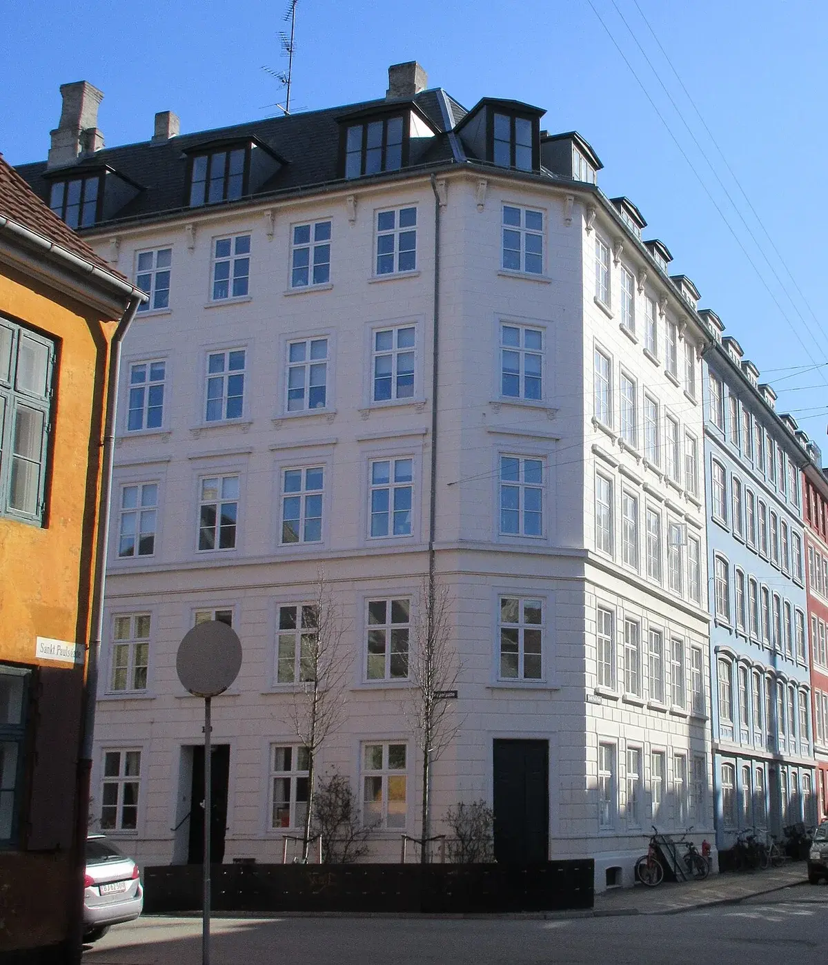 White corner apartment building on a street in Copenhagen.