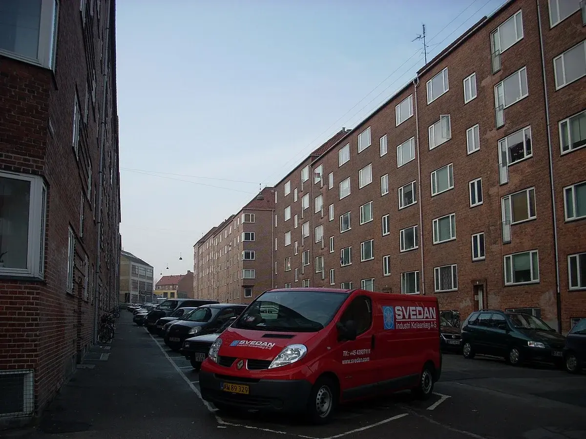 Quiet residential street with brick apartment buildings and parked cars in Copenhagen.