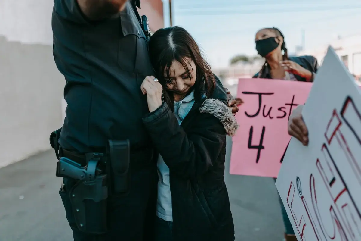 Young woman hugging police officer during protest