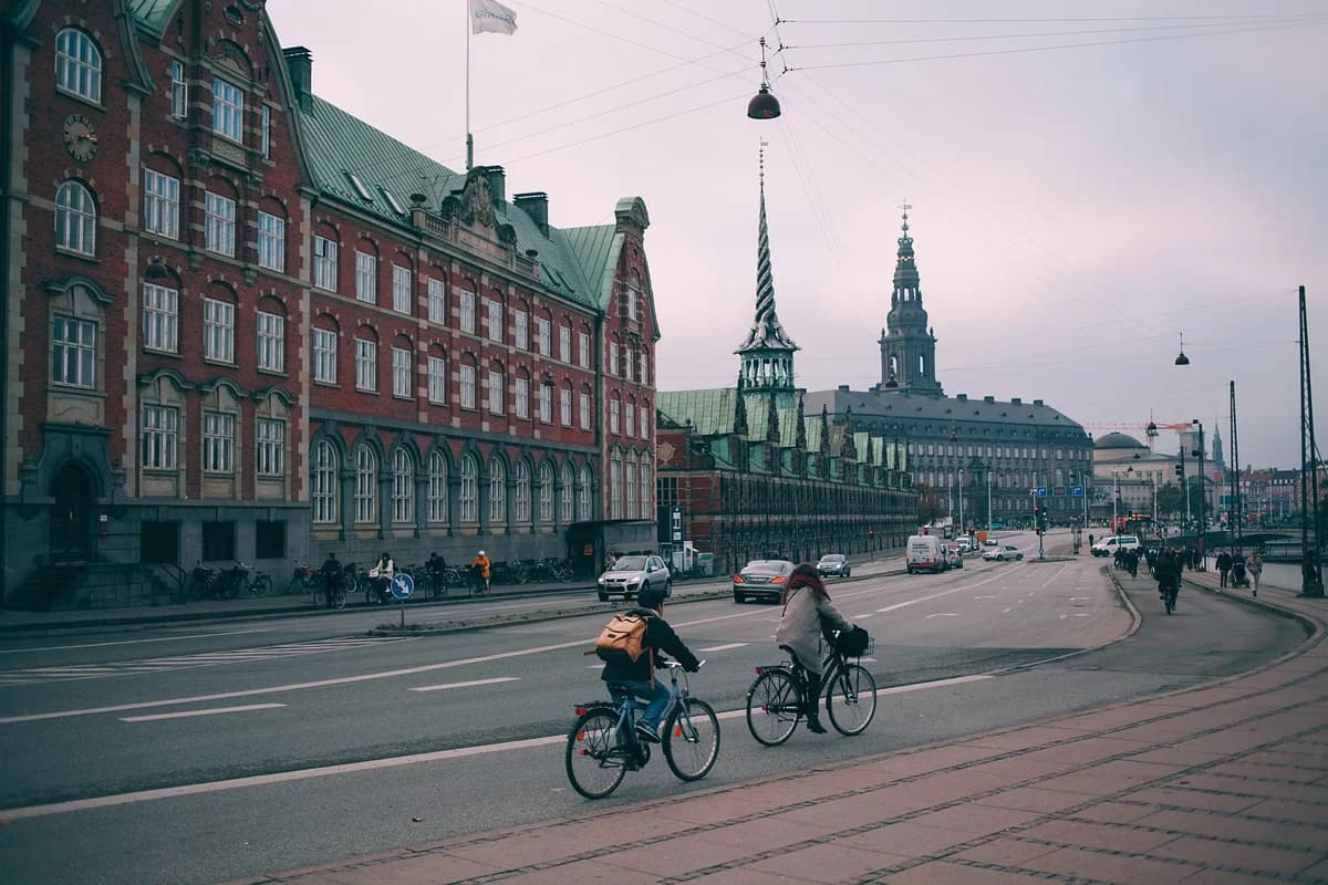 Cyclists riding along Copenhagen embankment with Christiansborg Palace in background