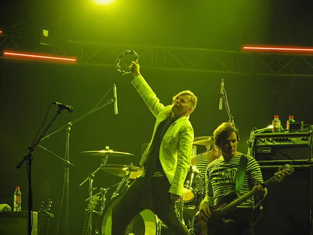 A rock band performing on stage under green concert lights.