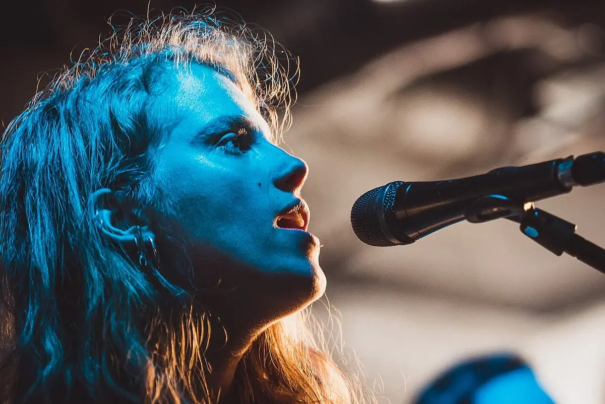 Close-up of Marika Hackman singing into a microphone on stage.