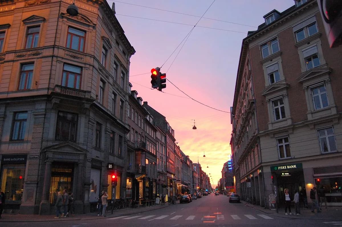 Sunset street view of Store Kongensgade in Copenhagen with historic buildings and traffic lights.