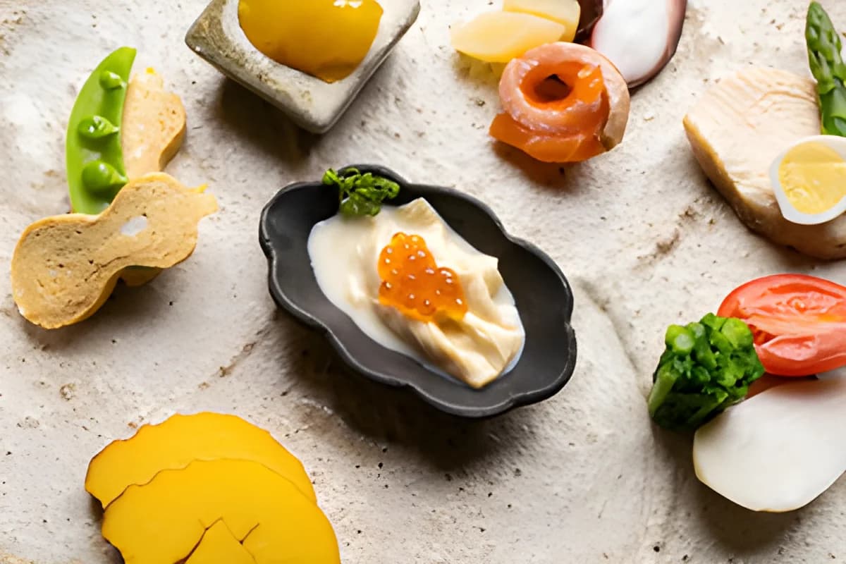 Japanese appetizers including fish roe, tamago, and vegetables on pottery plates