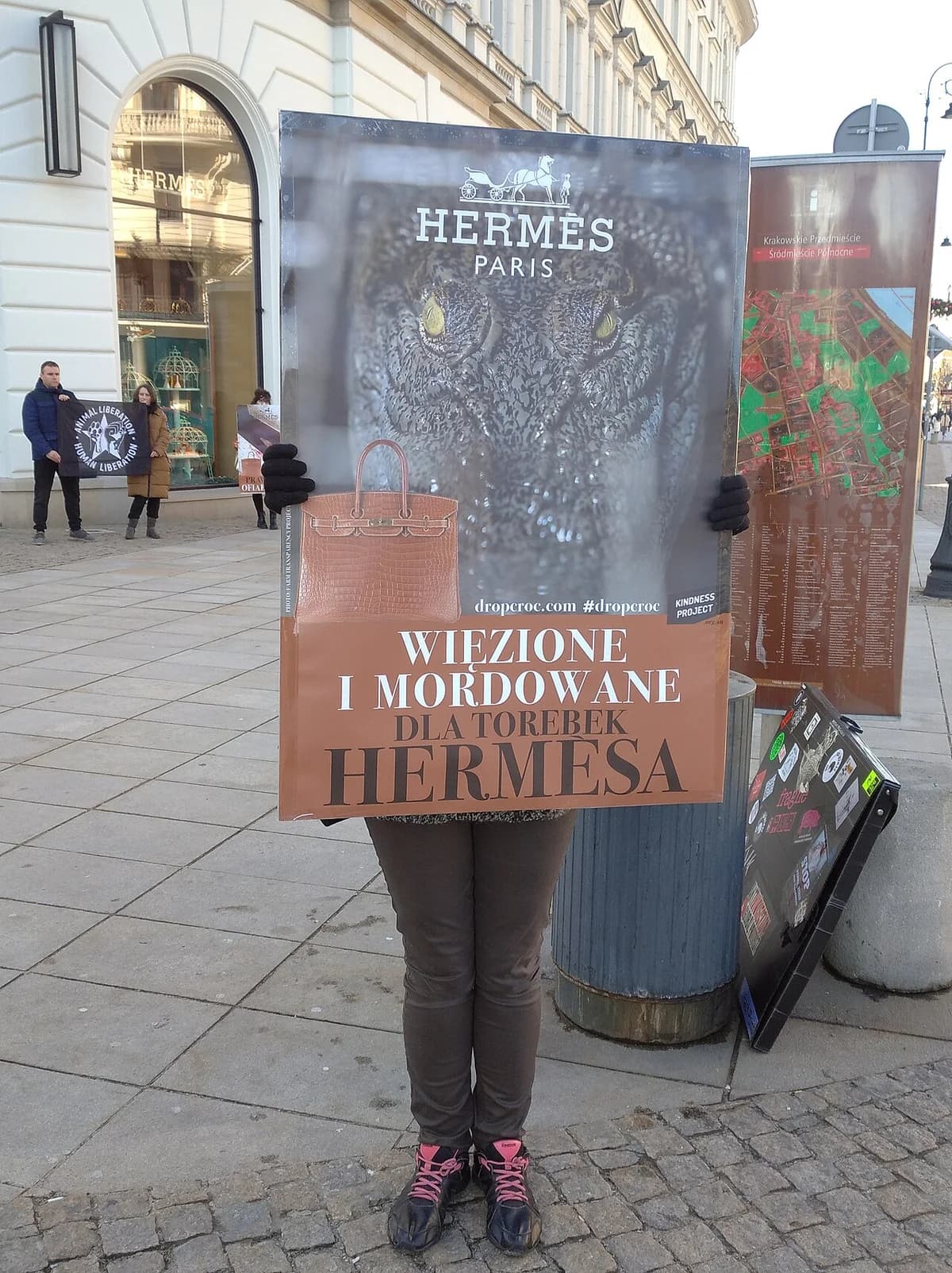Protester holding sign against use of crocodile skin handbags outside Hermès store in Warsaw