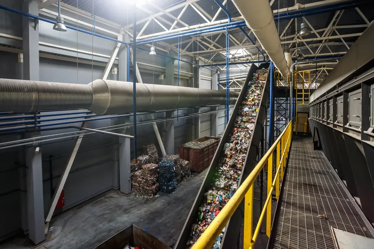 A conveyor belt carrying mixed recyclables inside a modern recycling plant.