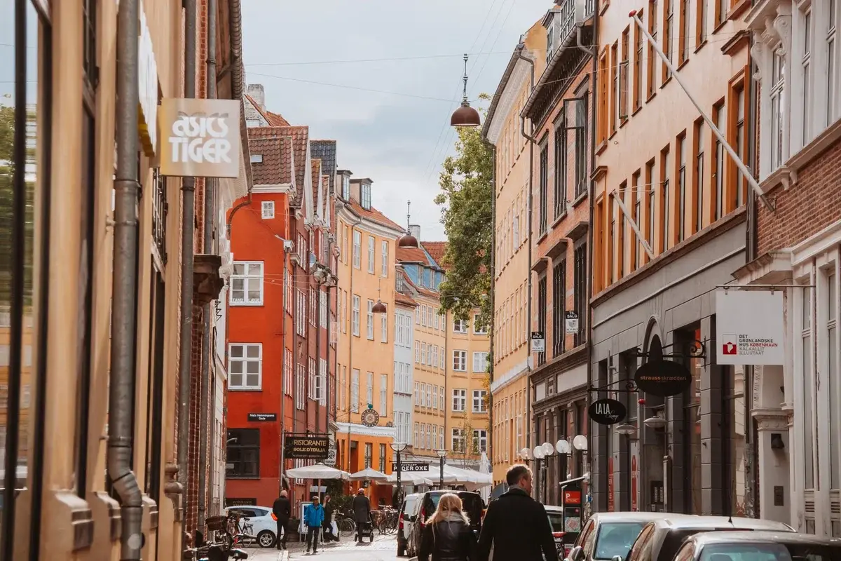 Colorful street scene in Copenhagen with historic buildings and pedestrians.