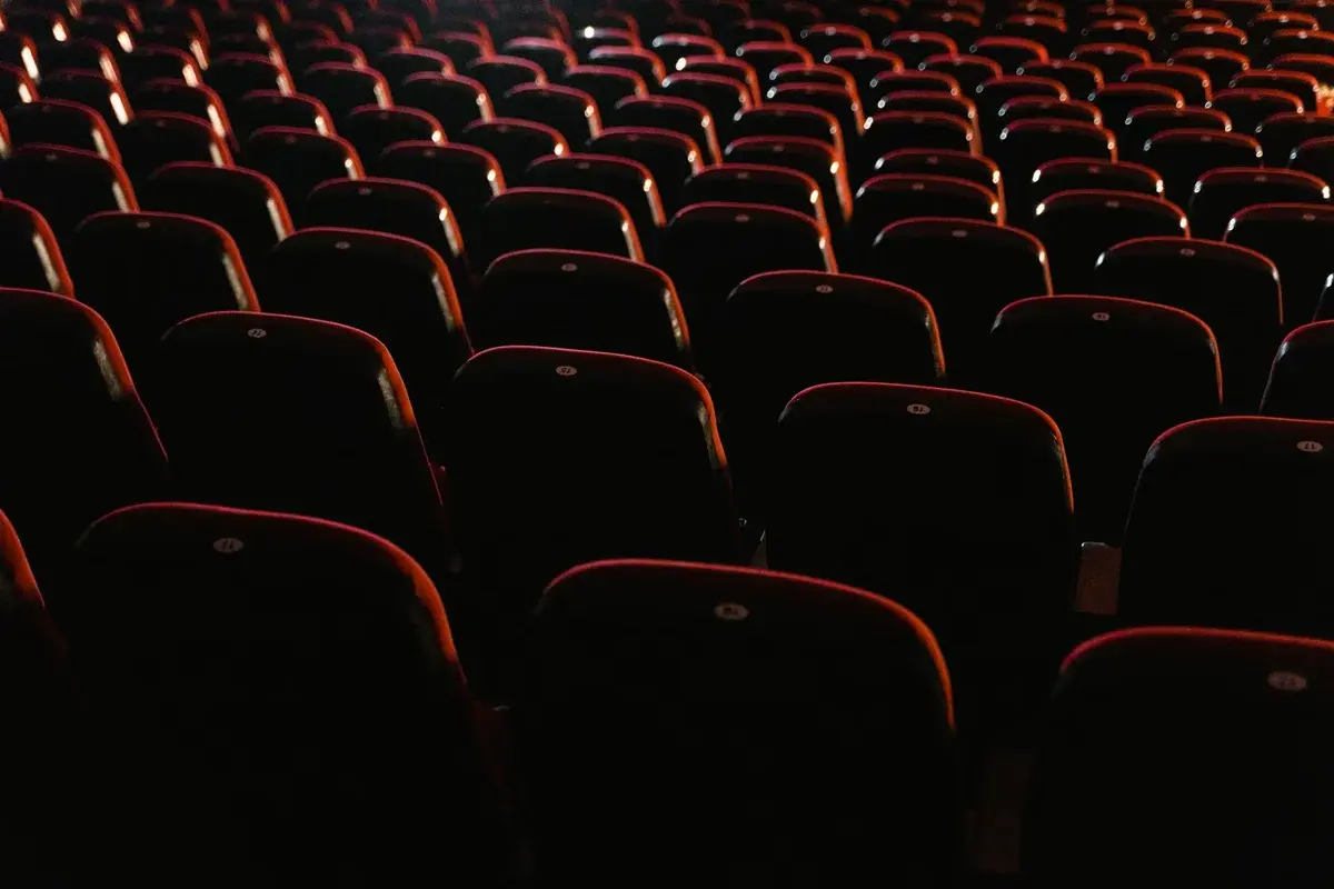 Rows of empty red seats in a dark cinema.
